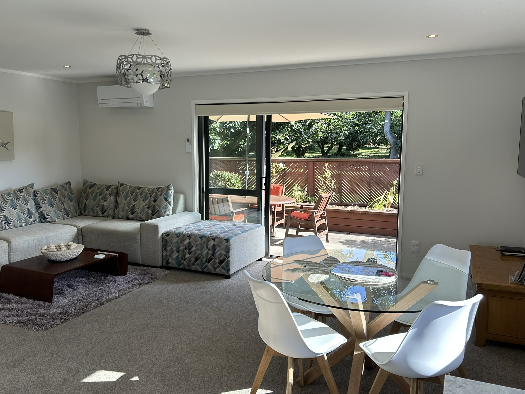 Open-plan lounge and dining at Baybell Lodge with orchard views through sliding doors