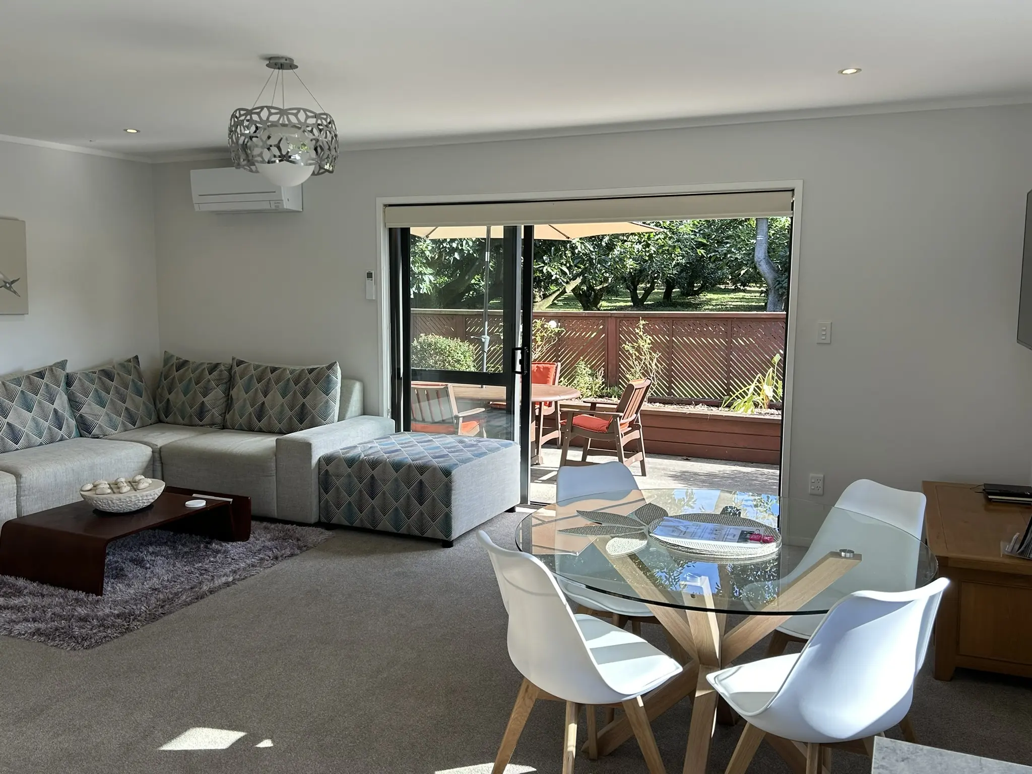 Open-plan lounge and dining at Baybell Lodge with orchard views through sliding doors