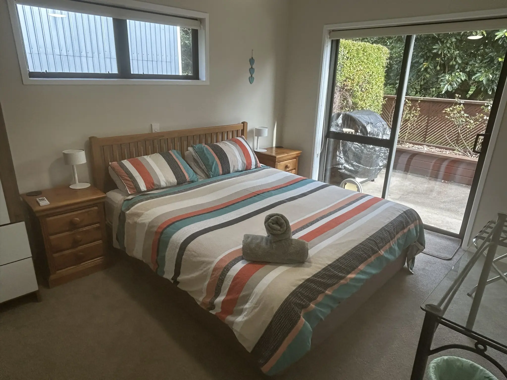 King bedroom with striped bedding and sliding door access to the private deck at Baybell Lodge